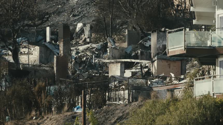 A part of a house is demolished with lots of debris scattered around it