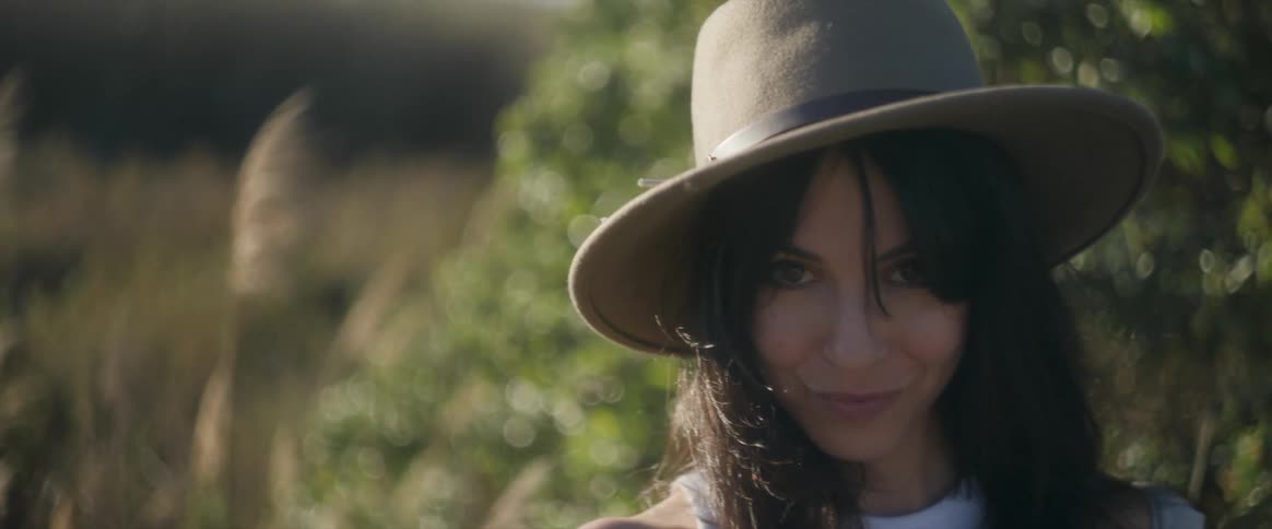 A woman wearing a hat is smiling on a sunny day