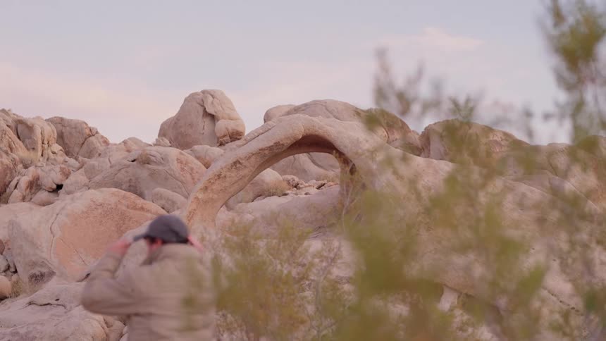 A clip of a person walking past a rocky hill