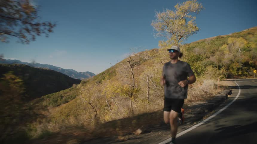 A man is slowly jogging up a mountain road