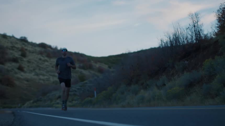 A man is running on the road by the hills