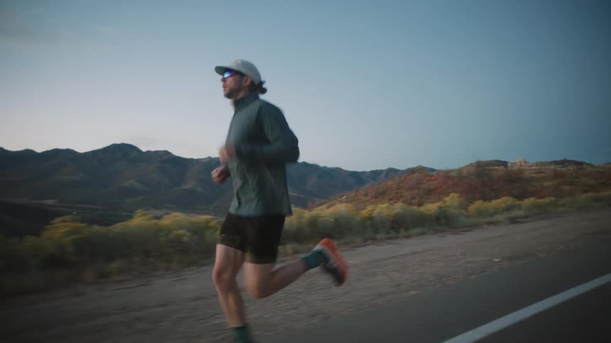 A man is running with mountains in the background