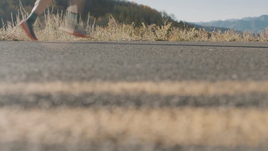 An adult runs along a remote highway on an autumn day