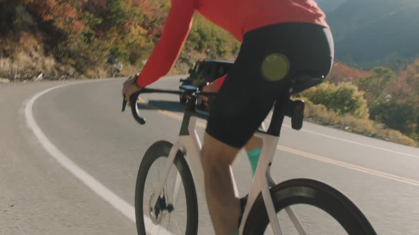 Cyclist riding on a highway surrounded by mountains and vegetation