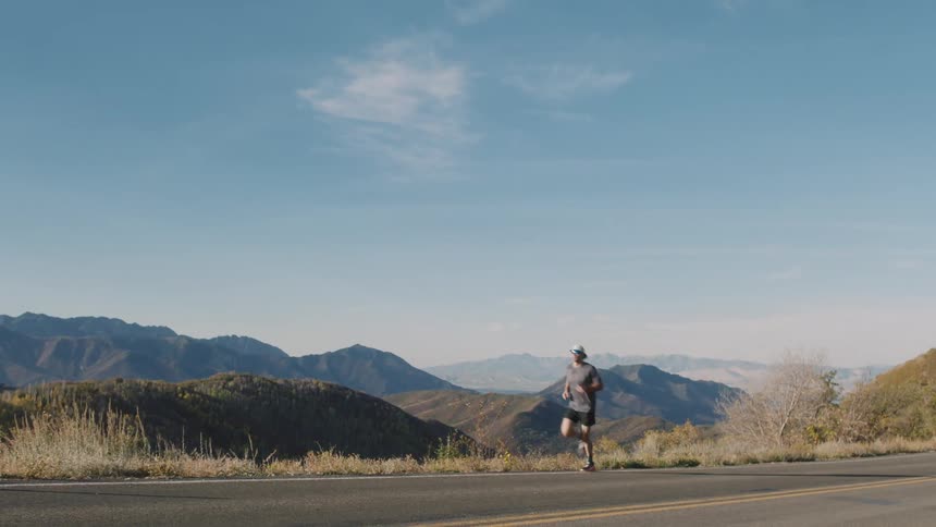 A man is running down the long road by the valley