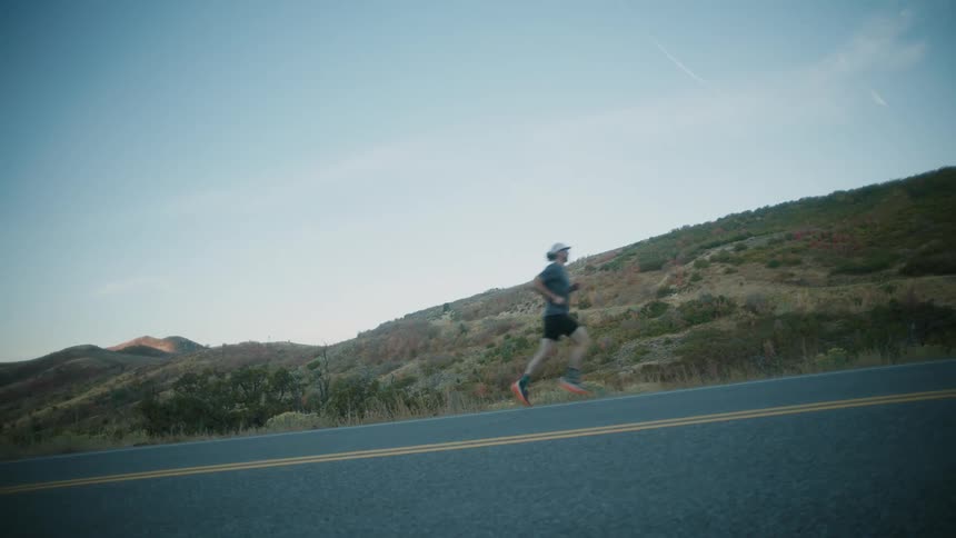 Man running on a highway with a mountain landscape