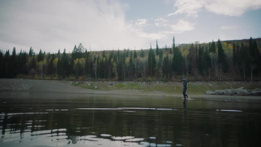 A man kicks through the water on the shore