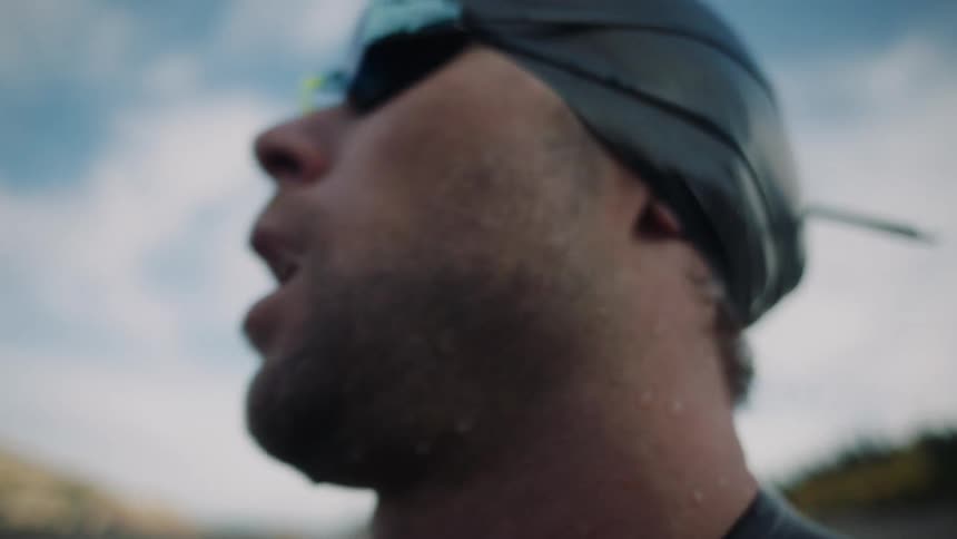 Man with swimming cap and goggles taking a deep breath