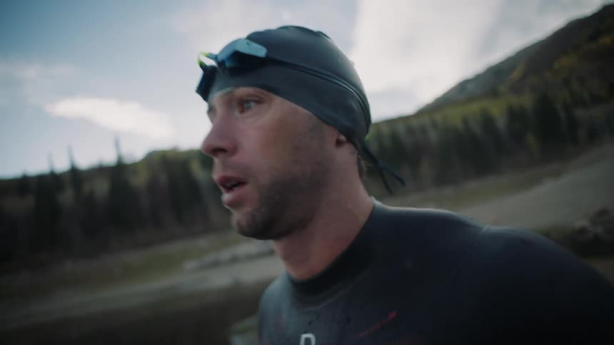 Man with swimming cap and goggles warming up and moving his arms