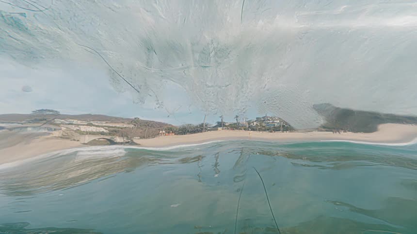 View from inside a wave transparency and the silhouette of the beach reflected in its curve