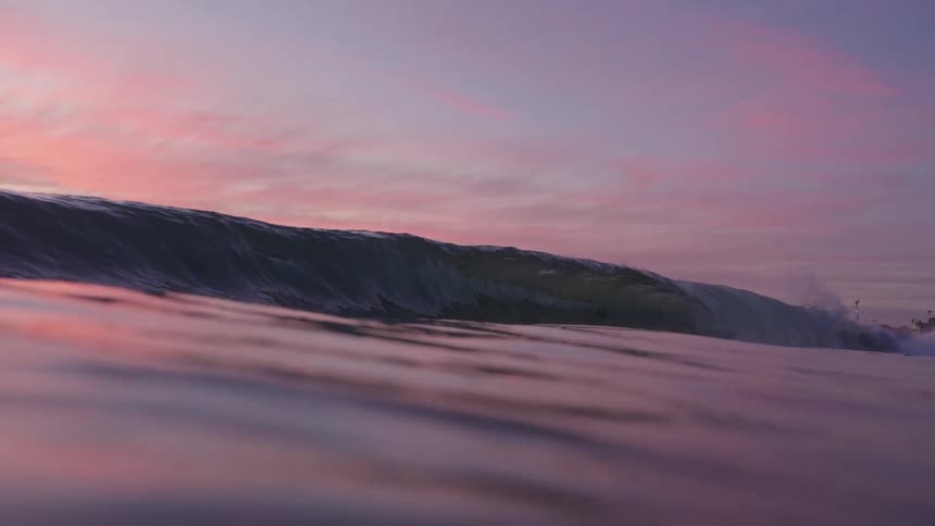 A large ocean wave is very slowly cresting and almost breaks completely