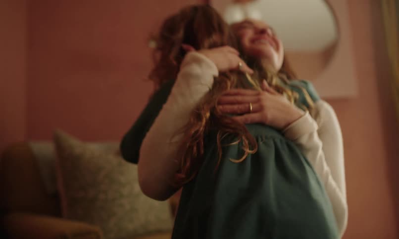 Girl runs towards her mother inside a room and gives her a hug
