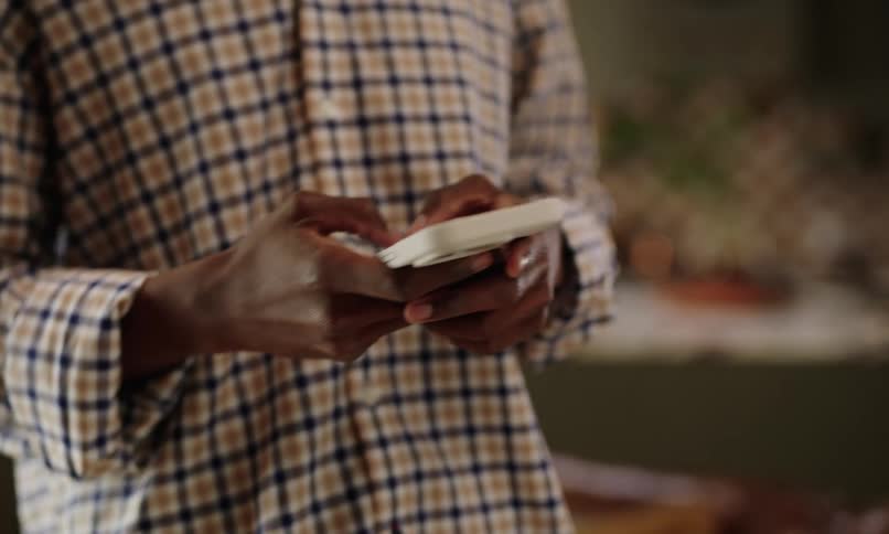 A person wearing a checkered shirt is texting on a phone