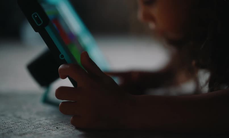 A girl is using her tablet on the floor