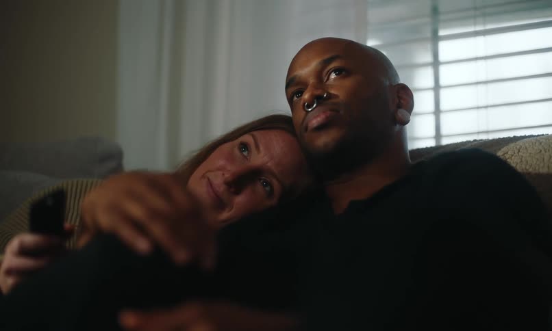 A couple hug on the couch while they watch something