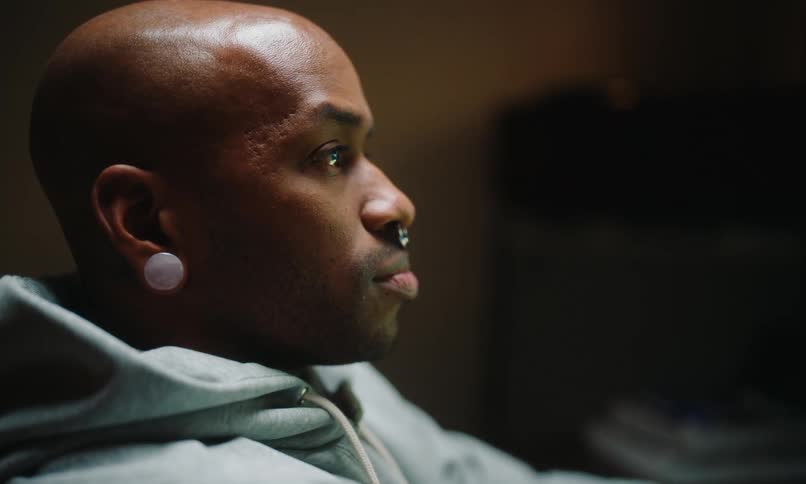 Man with a piercing sitting looking forward thoughtfully
