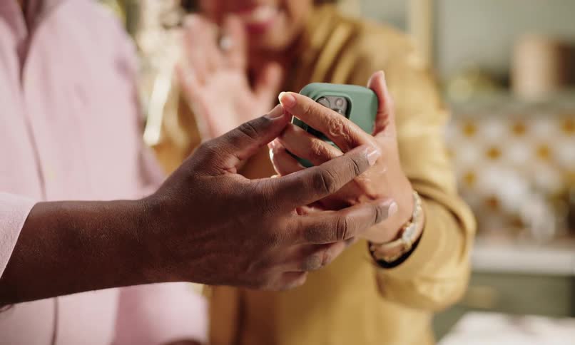 An image of a man and a woman holding a phone and waving hands