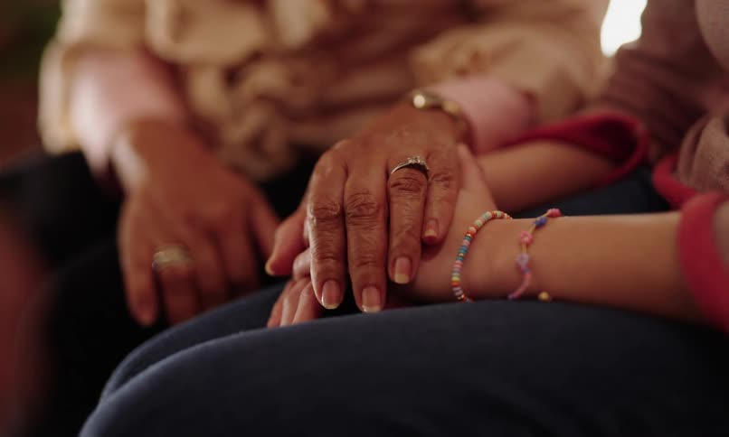 An older persons hand gently holding the hand of a younger person wearing a colorful bracelet conveying a sense of comfort and connection
