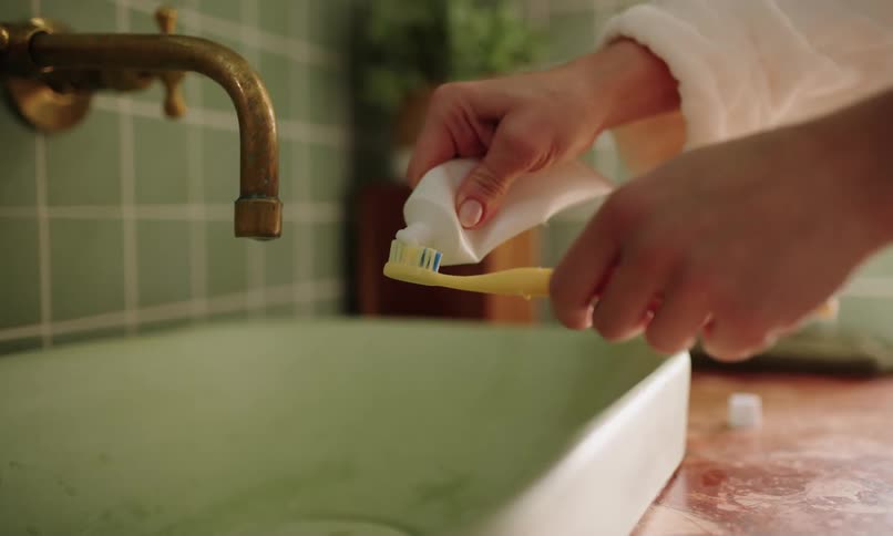 Person applies toothpaste to their toothbrush