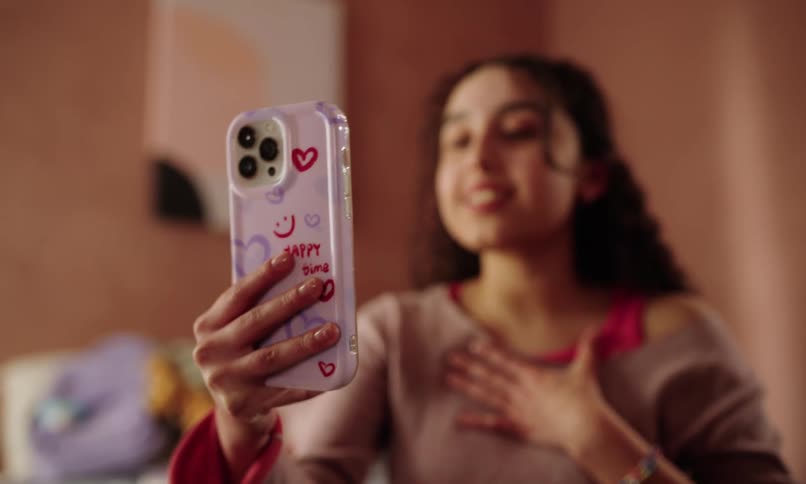 Teenage girl in her bedroom smiles and waves while talking during a video call