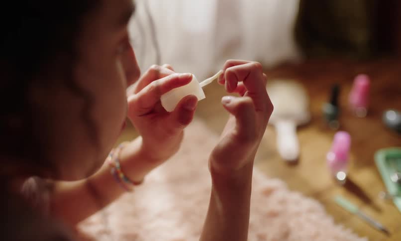 Teenager applies fingernail polish while indoors