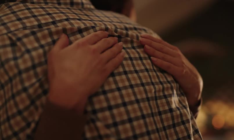 Close up of a womans pair of hands hugging a man