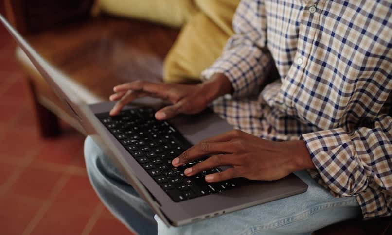 Pair of hands of a seated person typing on a laptop