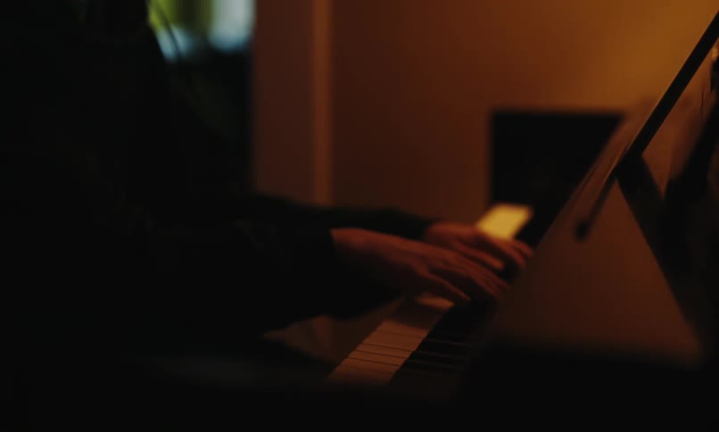 Man wearing headphones makes a selection on his tablet before playing the piano
