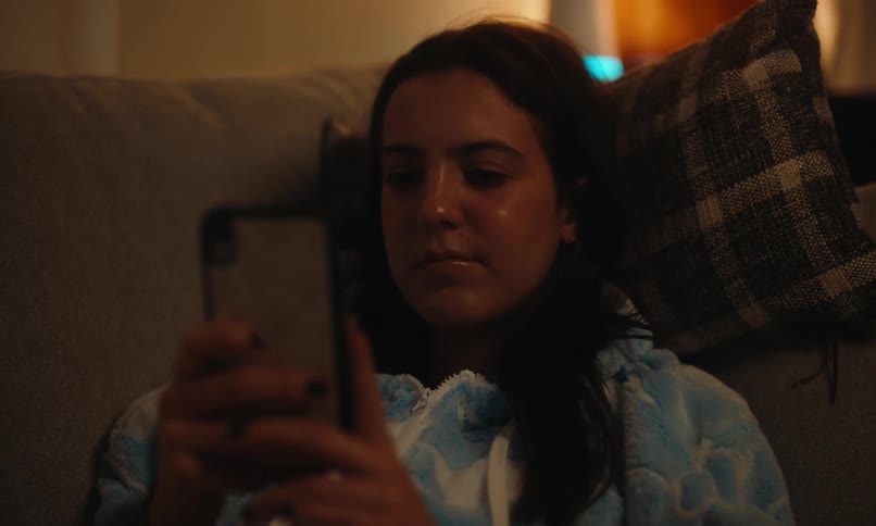 A girl is smiling while using her cell phone