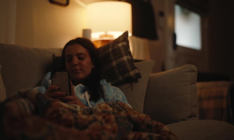 Woman lying on the couch interacting with a smartphone