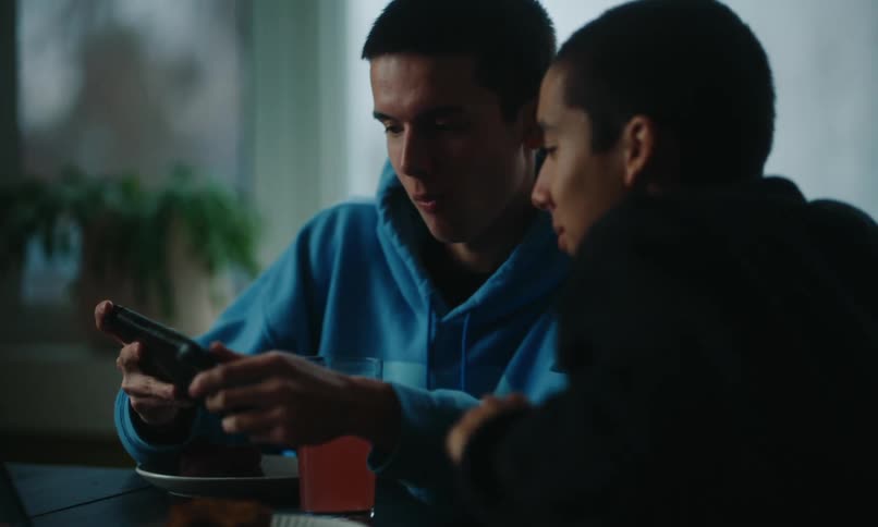 An image of two boys having a conversation while operating a smartphone