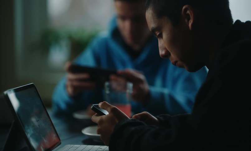 Two friends sitting playing on smartphone