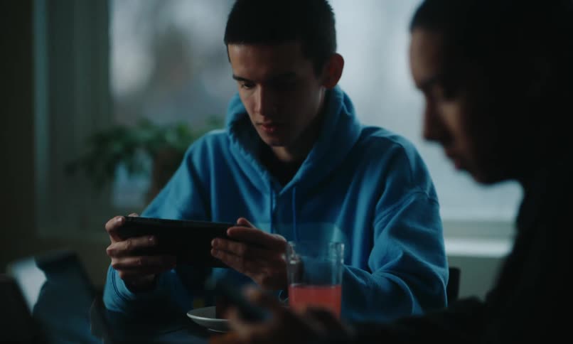 Friends having breakfast while using phones and laptops at the table