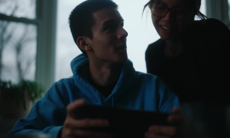 Mother approaching her teenage son who is playing on a smartphone