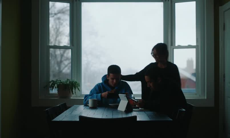 A footage of boys eating on the dinning table while operating a tab