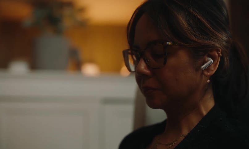 A woman drinks coffee and listens to her earbuds