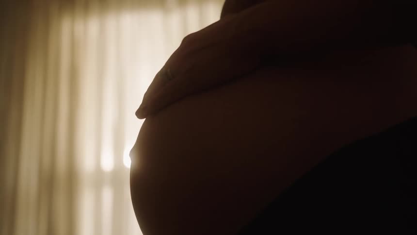 A woman is massaging her pregnant stomach