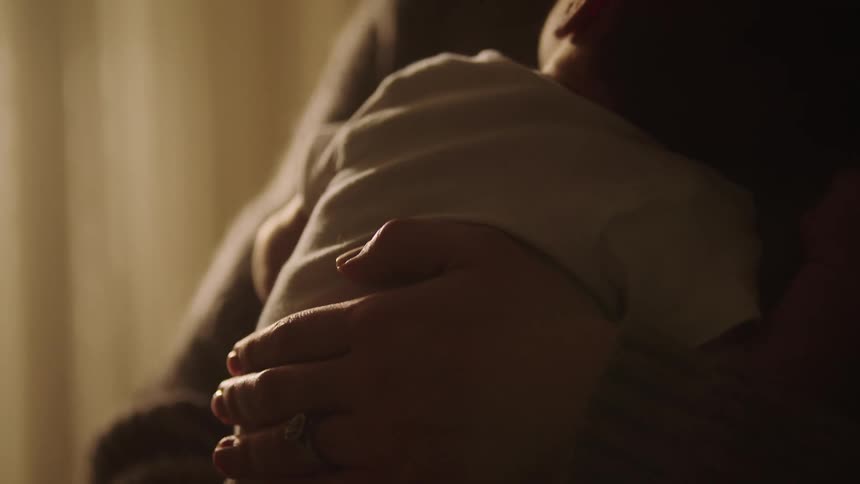 A mother holds her baby while rubbing his back
