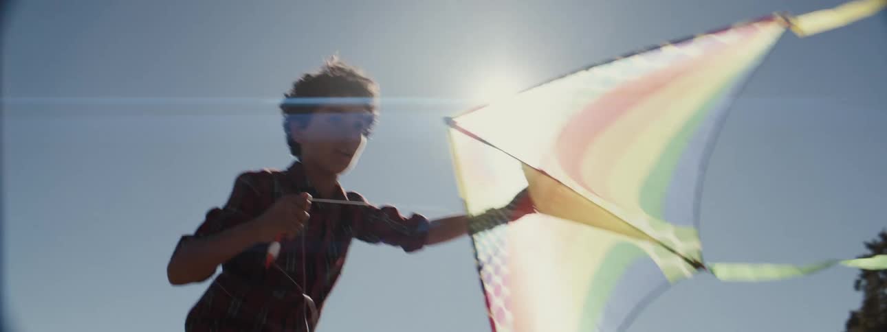 Boy running outdoors with a big kite