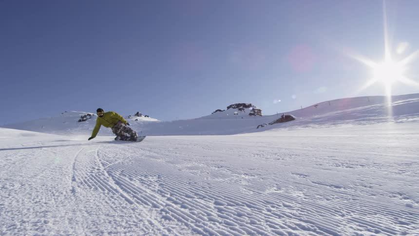A snowboarder speeds down a mountain