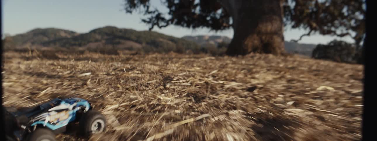 Remote control car moving through dry grass