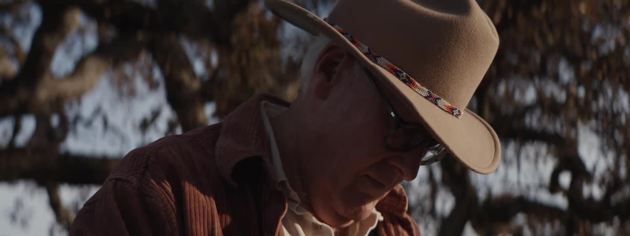 Man in hat painting a picture outdoors