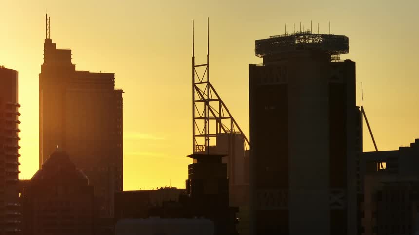 Aerial panorama of buildings silhouetted against a golden sky and sun