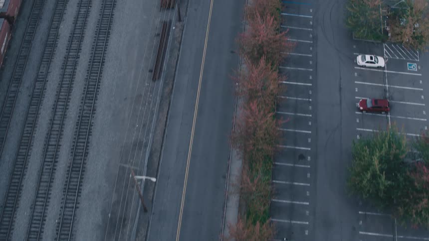 Aerial view of a street with a parking lot on a train line next to it