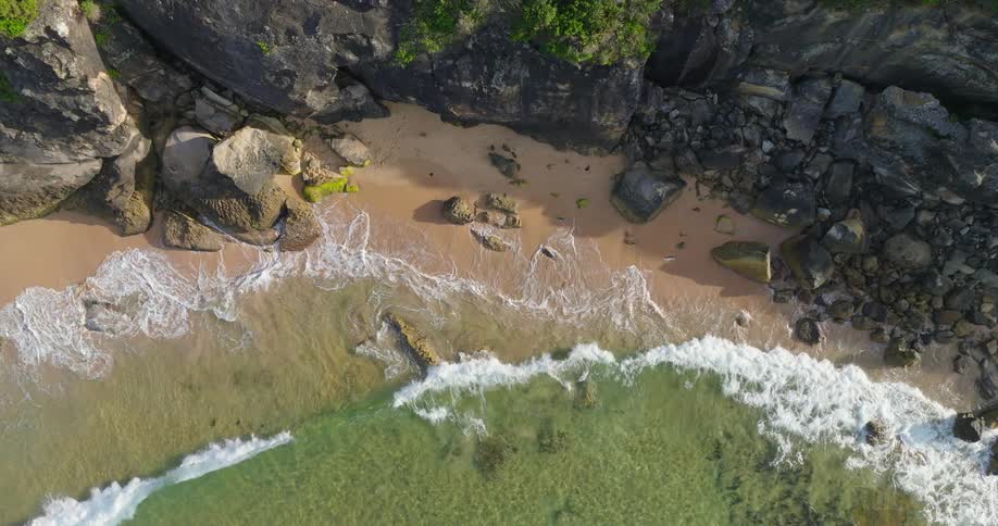 Aerial of ocean waves rolling into a rocky coastline