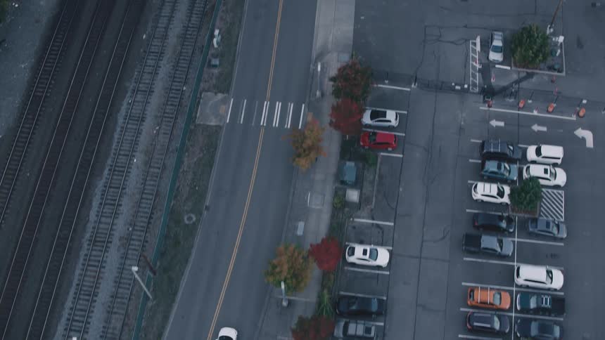 Vehicles travel along a highway paralleling the railroad tracks on an autumn day