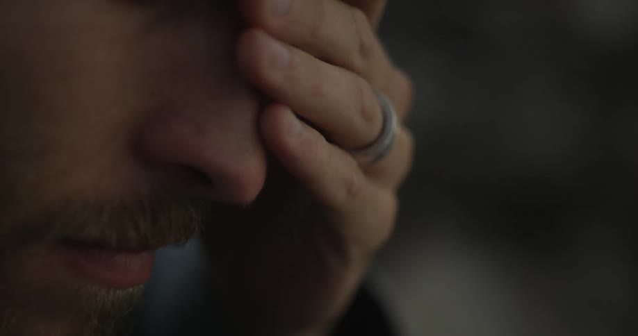 A close up of a man rubbing his face