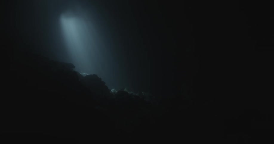 A dim light shines in the pitch black waters