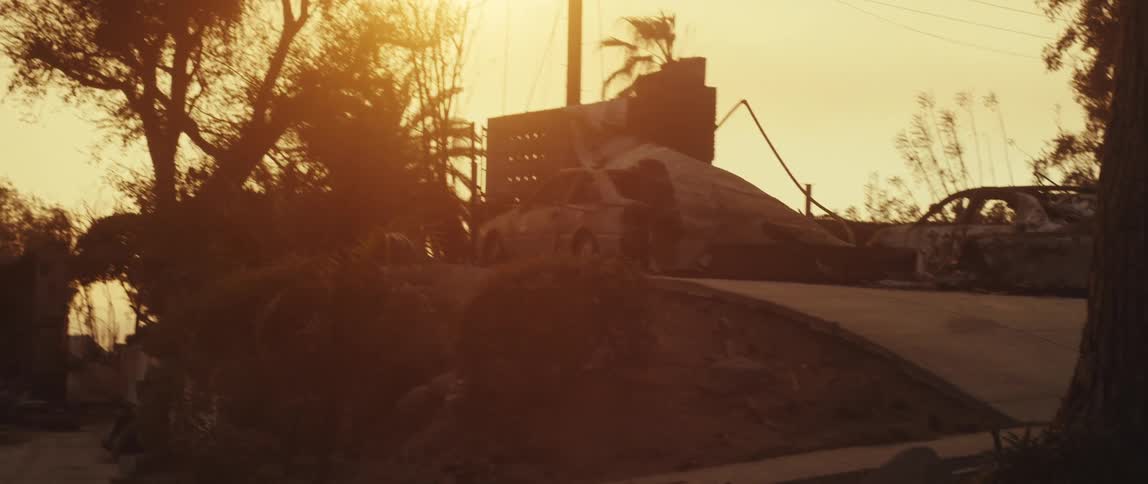 A sunlit hazy scene with a building under construction or partially destroyed surrounded by abandoned cars