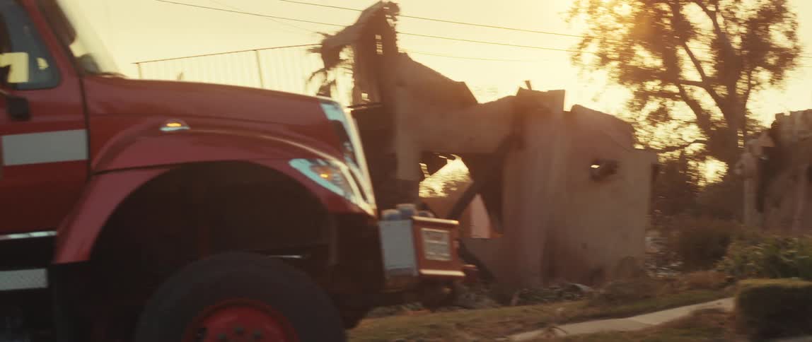 Fire truck parked next to an urban road with destroyed houses